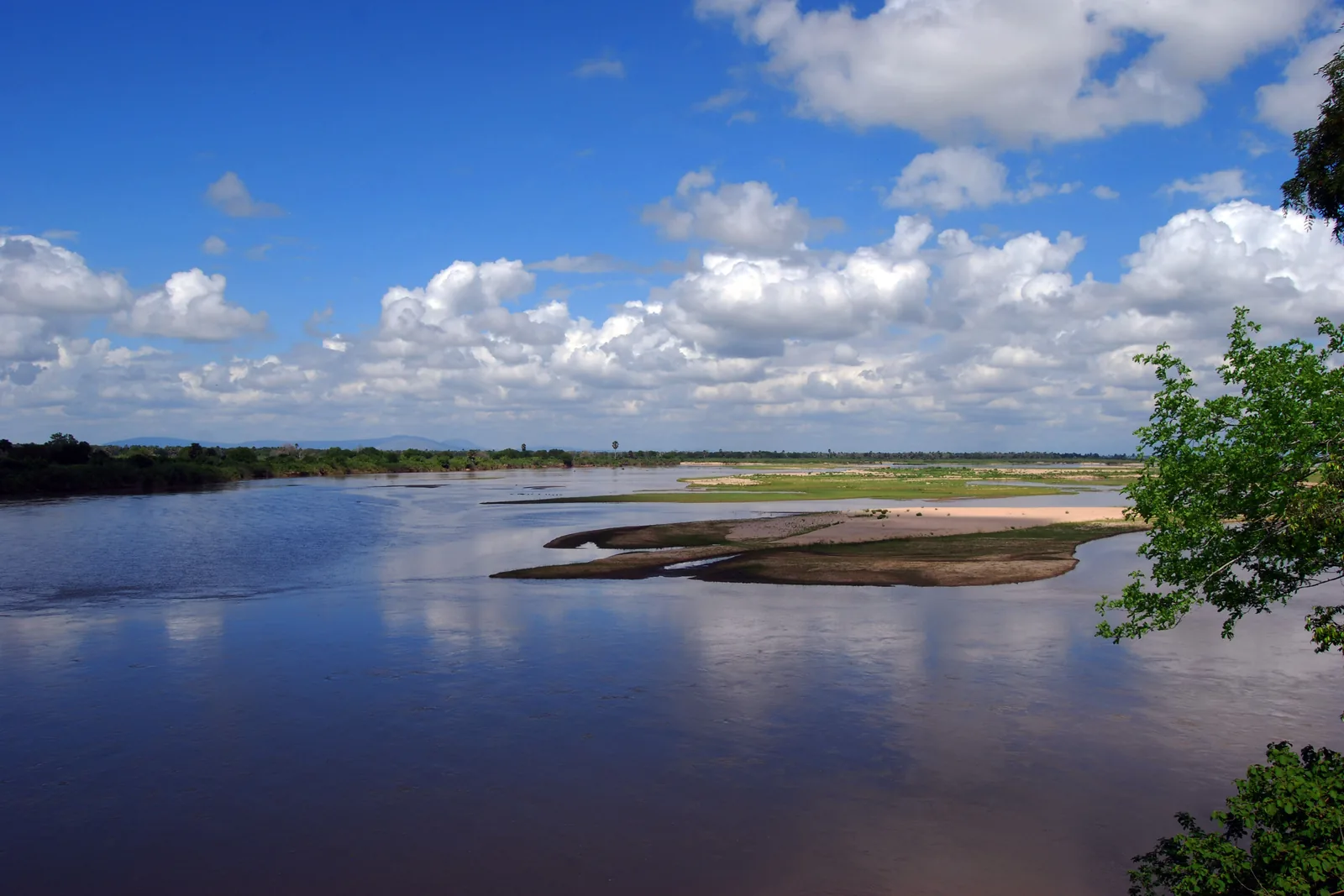 O largo e arenoso rio Rufiji, na antiga Reserva de Caça de Selous, sob um céu azul com nuvens dispersas